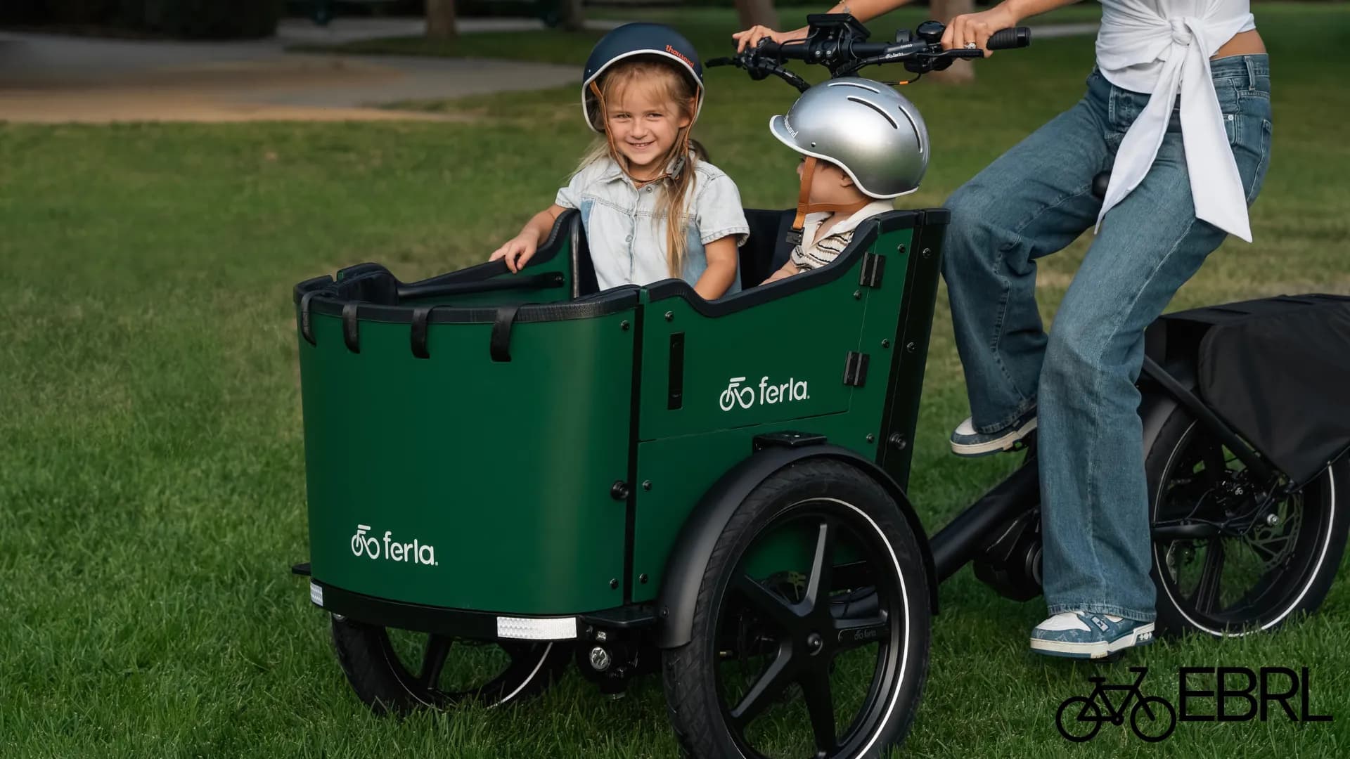 Ferla Royce MAX cargo trike carrying two children in a green front box on a park lawn